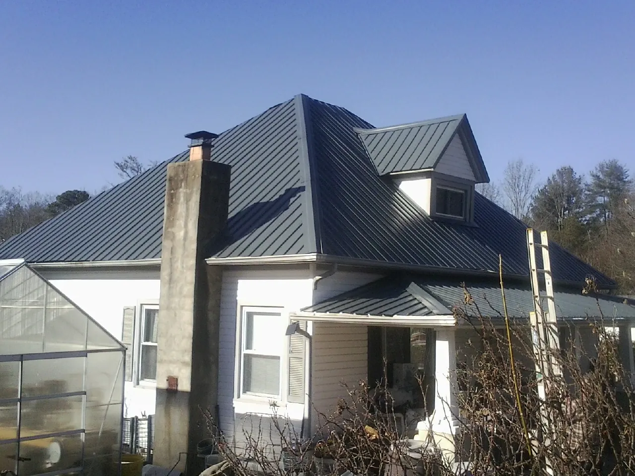 Dark blue standing seam metal roof on a white farmhouse with dormer — Slate & Tile Roof Repair by Roofing Brothers in Landisburg
