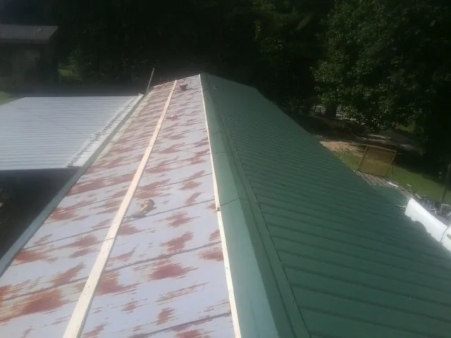 Old rusted panels beside newly installed green metal roofing — Wind Damage Roof Repair by Roofing Brothers in Landisburg