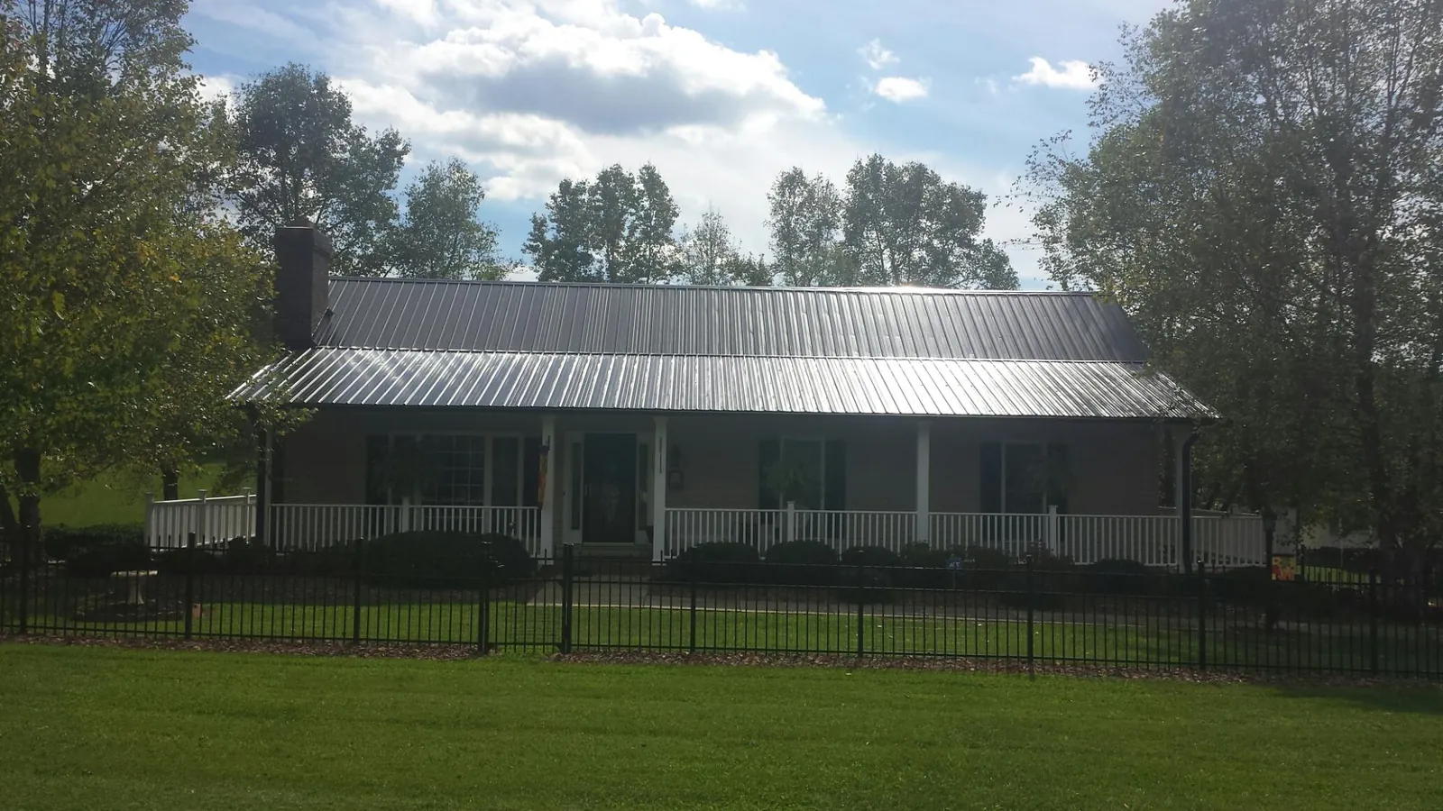 Gray metal roof on a brick ranch with a full width front porch — Gutter Guard Installation work by our crew in Landisburg