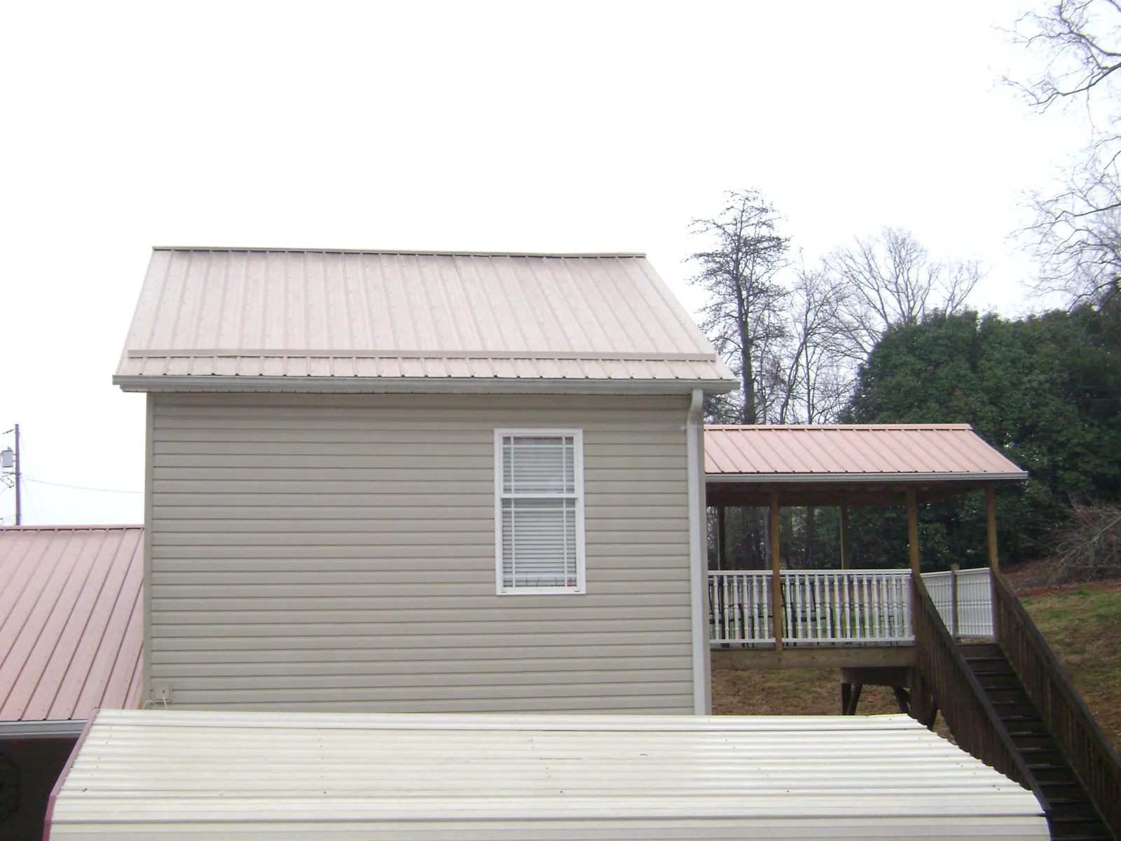 Tan metal roofs on a two story addition and attached porch, from a Roof Replacement job in Landisburg