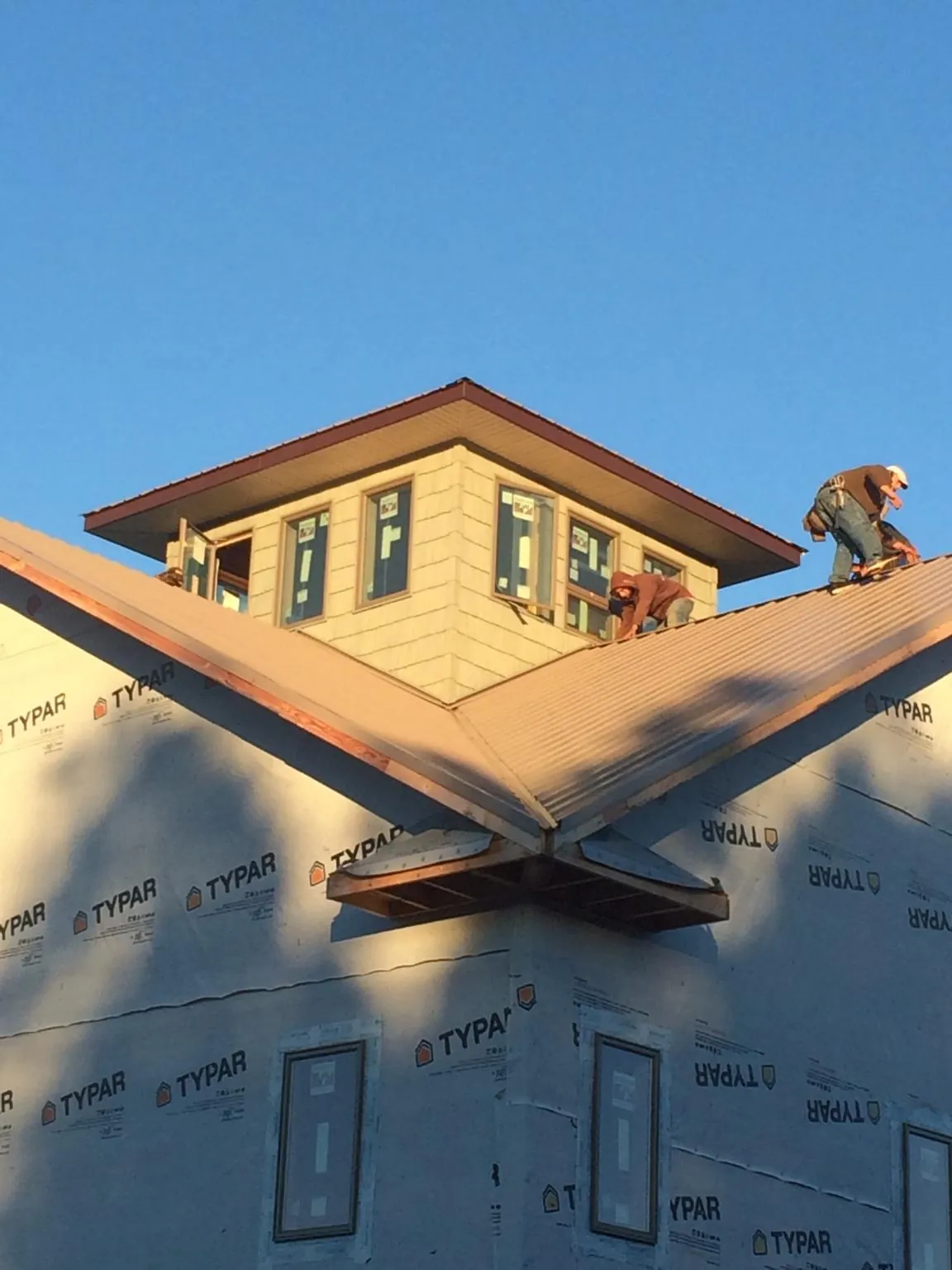 Roofers working around a rooftop cupola on a new metal roof at sunset — Roof Waterproofing in Landisburg by Roofing Brothers